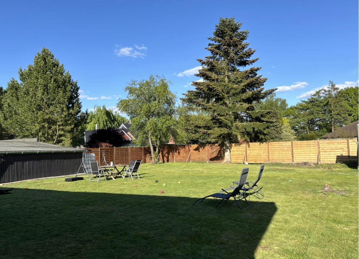 Großer, sicher eingezäunter Garten mit Rasenfläche, Bäumen und Liegestühlen